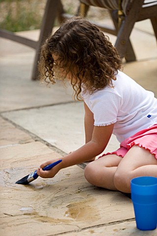 DESIGNER_CLARE_MATTHEWS_WATER_PAINTING__GIRL_PAINTING_WITH_WATER_ON_PATIO