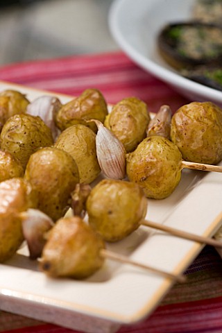 DESIGNER_CLARE_MATTHEWS__OUTDOOR_FOOD__ROASTED_WHOLE_POTATOES_WITH_GARLIC_CLOVES_ON_SKEWER