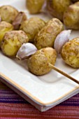 DESIGNER: CLARE MATTHEWS - OUTDOOR FOOD - ROASTED WHOLE POTATOES WITH GARLIC CLOVES ON SKEWER