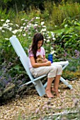 DESIGNER: CLARE MATTHEWS - WOODEN BENCH AND TABLE PROJECT: WOODEN BENCH AND TABLE IN GRAVEL GARDEN WITH GIRL AND GUINEA PIG