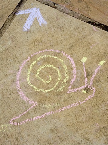 DESIGNER_CLARE_MATTHEWS_SNAKES_AND_LADDERS_CHALK_DRAWING_OF_SNAIL_ON_PATIO