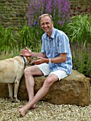 RICKYARD BARN GARDEN  NORTHAMPTONSHIRE: CLIVE SITTING ON A ROCK WITH MURPHY THE DOG