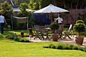 RICHARD JACKSONS GARDEN. DESIGNED BY CLARE MATTHEWS - PATIO  BOX BALLS  TABLE AND CHAIRS  PARASOL  CHILDREN PLAYING BADMINTON
