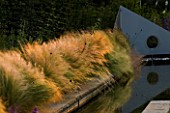 RICHARD JACKSONS GARDEN. DESIGNED BY CLARE MATTHEWS - WATER FEATURE - RECTANGULAR POOL/ POND WITH STIPA TENUISSIMA  METAL SAIL WITH WATERFALL
