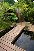 KATHY TAYLORS GARDEN  LONDON: POND - POND WITH DECKED WALKWAY  SCULPTURE AND FENCE MADE FROM WOODEN POSTS