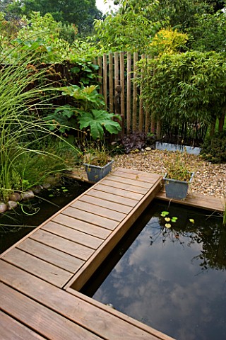 KATHY_TAYLORS_GARDEN__LONDON_POND__POND_WITH_DECKED_WALKWAY__SCULPTURE_AND_FENCE_MADE_FROM_WOODEN_PO