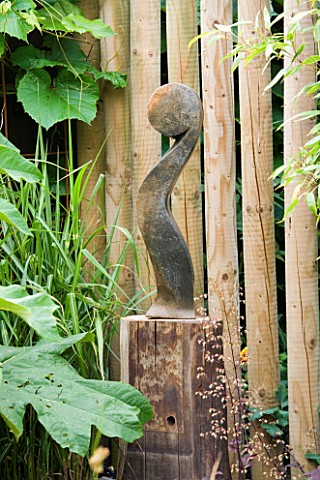 DESIGNER_KATHY_TAYLOR__LONDON__AFRICAN_SCULPTURE_IN_FRONT_OF_SCREEN_MADE_FROM_WOODEN_POSTS
