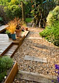 KATHY TAYLORS GARDEN  LONDON: BACK GARDEN VIEW ALONG GRAVEL PATH WITH SLEEPERS. DECKING WITH THREE CONTAINERS AND POND/ POOL