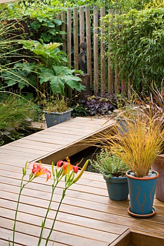 KATHY_TAYLORS_GARDEN__LONDON_DECKED_TERRACE_AND_WALKWAY_BESIDE_POND_WITH_CONTAINERS_AND_AFRICAN_SCUL