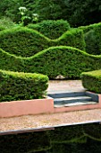 VEDDW HOUSE GARDEN  GWENT  WALES: DESIGNERS ANNE WAREHAM AND CHARLES HAWES - YEW HEDGES BESIDE THE REFLECTING POOL