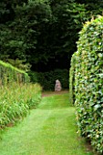 VEDDW HOUSE GARDEN  GWENT  WALES: DESIGNERS ANNE WAREHAM AND CHARLES HAWES - VIEW ALONG HEDGE LINED AVENUE TO STONE SCULPTURE - FOCAL POINT