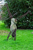 WOODPECKERS  WARWICKSHIRE  WINTER: SCULPTURE OF MAN DOING A HANDSTAND IN LAWN