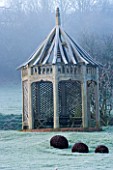 WOODPECKERS  WARWICKSHIRE  WINTER: FROSTED LAWN WITH METAL SCULPTURE AND WOODEN SUMMERHOUSE
