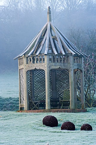 WOODPECKERS__WARWICKSHIRE__WINTER_FROSTED_LAWN_WITH_METAL_SCULPTURE_AND_WOODEN_SUMMERHOUSE
