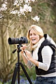 BLOND HAIRED GIRL WITH 35MM SLR DIGITAL CAMERA IN A GARDEN