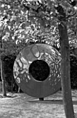 DESIGNER: DAVID HARBER. GARDEN DESIGNED BY ANGEL COLLINS - RUSTY METAL CIRCLE SCULPTURE AT THE END OF A HORNBEAM AVENUE. BLACK AND WHITE IMAGE