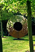DESIGNER: DAVID HARBER. GARDEN DESIGNED BY ANGEL COLLINS - RUSTY METAL CIRCLE SCULPTURE AT THE END OF A HORNBEAM AVENUE.