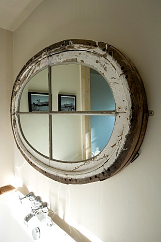 BOONSHILL_FARM__EAST_SUSSEX_INTERIOR_OF_BATHROOM_WITH_OVAL_MIRROR_MADE_FROM_OLD_WINDOW_ABOVE_BATH_DE