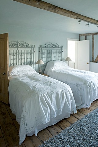 BOONSHILL_FARM__EAST_SUSSEX_INTERIOR_OF_GUEST_BEDROOM_WITH_ANTIQUE_LACE_BEDSPREADS_AND_METAL_GATES_A