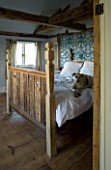 BOONSHILL FARM  E SUSSEX. INTERIOR OF BEDROOM WITH HONEY THE DOG ON RECLAIMED WOODEN BED BY MICK SHAW FROM OLD STAIRCASE AND FLOORBOARDS.  LISETTE PLEASANCE