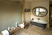 BOONSHILL FARM  EAST SUSSEX. INTERIOR OF BATHROOM WITH ROLLTOP (CLAWFOOT) BATH  WOODEN BENCH FROM INDIA  AND MIRROR MADE FROM OLD WINDOW. DESIGNER:  LISETTE PLEASANCE