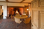 BOONSHILL FARM  EAST SUSSEX. INTERIOR OF KITCHEN WITH INGLENOOK FIREPLACE  TABLE AND CHAIRS  TRIPOD LAMP AND ORIGINAL BRICK FLOOR. DESIGNER: LISETTE PLEASANCE