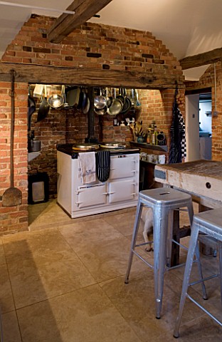 BOONSHILL_FARM__E_SUSSEX_INTERIOR_OF_KITCHEN_WITH_AGA__BRICK_CANOPY_WITH_PANS__OLD_BUTCHERS_BLOCK_GA