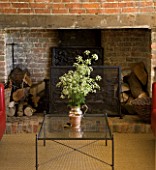 BOONSHILL FARM  EAST SUSSEX. INTERIOR OF LIVING ROOM WITH INGLENOOK FIREPLACE WITH EXPOSED BRICK  NATURAL SISAL FLOOR AND COW PARSLEY IN SILVER VASE. DESIGNER : LISETTE PLEASANCE