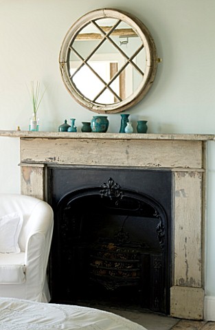 BOONSHILL_FARM__EAST_SUSSEX_INTERIOR_OF_BEDROOM_WITH_FIREPLACE_AND_MIRROR_MADE_FROM_OLD_WINDOW_POTTE