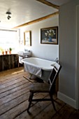 BOONSHILL FARM  EAST SUSSEX. INTERIOR OF BATHROOM WITH OLD ROLLTOP (CLAWFOOT) BATH & ANTIQUE CHAIR FROM INDONESIA. SHELVING MADE FROM TREE TRUNKS BY MICK SHAW. D: LISETTE PLEASANCE