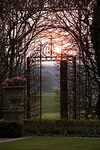 HOLKER_HALL__CUMBRIA__SUNSET_WITH_ORNATE_METAL_GATE_IN_THE_SUNKEN_GARDEN