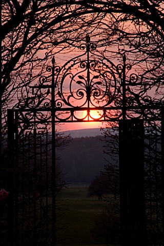 HOLKER_HALL__CUMBRIA__SUNSET_WITH_ORNATE_METAL_GATE_IN_THE_SUNKEN_GARDEN