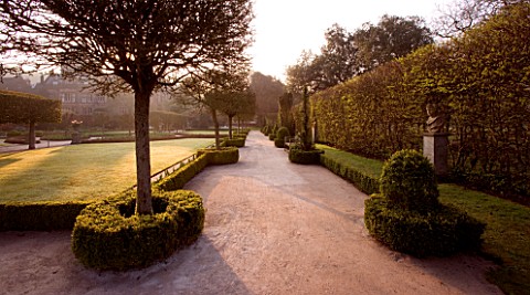HOLKER_HALL__CUMBRIA__THE_SUNKEN_GARDEN_AT_DUSK_WITH_BOX_HEDGING__LAWN_AND_STATUARY_FORMAL_GARDEN