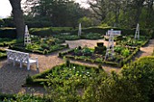 KELMARSH HALL  NORTHAMPTONSHIRE: FORMAL GARDEN IN WOODLAND IN SPRING WITH WHITE BENCHES AND TRIPODS