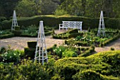 KELMARSH HALL  NORTHAMPTONSHIRE: FORMAL GARDEN IN WOODLAND IN SPRING WITH BOX HEDGING  TULIPS  WHITE BENCH AND TRIPODS