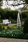 KELMARSH HALL  NORTHAMPTONSHIRE: THE SUNKEN GARDEN IN SPRING WITH WHITE TULIPS AND NARCISSI  A WOODEN TRIPOD AND ORNATE SEAT/ BENCH