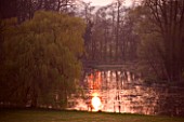 KELMARSH HALL  NORTHAMPTONSHIRE: VIEW OF THE LAKE AND SETTING SUN WITH WEEPING WILLOW