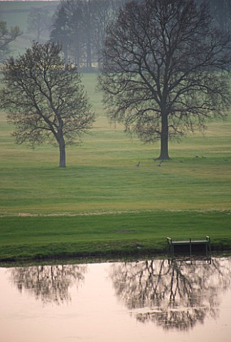 KELMARSH_HALL__NORTHAMPTONSHIRE_VIEW_OF_THE_LAKE_IN_THE_EVENING_WITH_TREES_AND_LANDSCAPE_BEYOND_PEAC