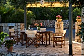 CORFU  GREECE. MALAMA HOUSE NEAR BARBATI. PATIO DINING AREA WITH TABLE AND CHAIRS SET FOR ALFRESCO DINING. EVENING LIGHT  ROMANTIC  AMBIENCE  RELAXING  RELAXED