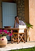 CORFU  GREECE. MAN (AGED 35) TALKING ON A MOBILE PHONE AT A TABLE. PATIO  TABLE AND CHAIRS. RELAXED  BUSINESS  SITTI NG