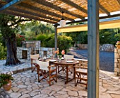 CORFU  GREECE. MALAMA HOUSE NEAR BARBATI. PATIO DINING AREA WITH TABLE AND CHAIRS AND BARBEQUE SET FOR ALFRESCO DINING. EVENING LIGHT  ROMANTIC  AMBIENCE  RELAXING  RELAXED