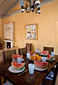 CORFU  GREECE. MALAMA HOUSE NEAR BARBATI. LIVING/ DINING ROOM WITH TABLE AND CHAIRS SET FOR DINING. WATER MELONS ON TABLE