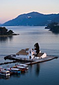 CORFU  GREECE: VIEW OF PONTIKONISSI OR MOUSE ISLAND AND VLACHERNA WITH ITS WHITE CONVENT  AT SUNSET. PLANE FLYING IN TO LAND
