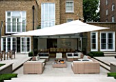 URBAN CONTEMPORARY MODERN MINIMALIST GARDEN DESIGNED BY CHARLOTTE SANDERSON: VIEW FROM LAWN TO THE HOUSE WITH PATIO WITH TABLE AND CHAIRS  AWNING OVERHEAD