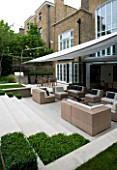 URBAN CONTEMPORARY MODERN MINIMALIST GARDEN DESIGNED BY CHARLOTTE SANDERSON: VIEW TO THE HOUSE WITH PATIO WITH TABLE AND CHAIRS  AWNING OVERHEAD  STEPS UP TO LAWN