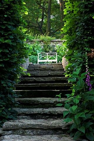 THE_OLD_RECTORY__HASELBECH__NORTHAMPTONSHIRE__STONE_STEPS_LEAD_UP_TO_A_WHITE_METAL_SEAT_IN_THE_FORMA