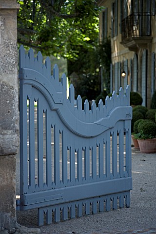 DESIGNER_DOMINIQUE_LAFOURCADE__PROVENCE__FRANCE___ORNATE_BLUE_WOODEN_GATE_WITH_FARMHOUSE_BEHIND_AND_