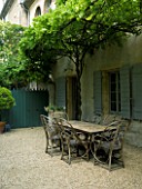 DESIGNER DOMINIQUE LAFOURCADE  PROVENCE  FRANCE - GRAVEL COURTYARD WITH TABLE AND CHAIRS AND PERGOLA. A PLACE TO SIT