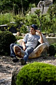 PROVENCE  FRANCE. GARDEN OF MARCO NUCERA. MARCO NUCERA SITTING ON ONE OF HIS WOODEN CHAIRS