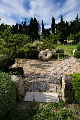 PROVENCE__FRANCE_GARDEN_OF_MARCO_NUCERA_GRAVEL_GARDEN_WITH_WOODEN_SCULPTURE__STONE_WATER_TROUGH__WOO